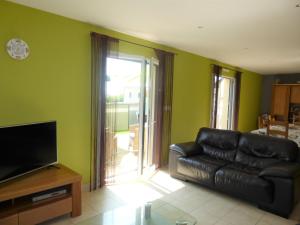 sala de estar con sofá de cuero negro y TV en Cottage, Le Pouldu, en Le Pouldu