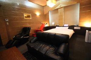 Habitación de hotel con cama y sofá de cuero en Utovilla HOTEL555 沼津店, en Numazu