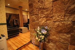 a lobby with a stone wall with a vase of flowers at Utovilla HOTEL555 沼津店 in Numazu +15 photos