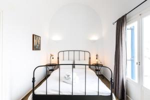 1 dormitorio con cama de metal y ventana en Arcana Santorini Villas, An Authentic Cycladic Experience en Akrotiri