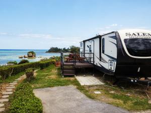 uma caravana estacionada na relva perto do oceano em Wood Pecker Nakijin em Nakijin