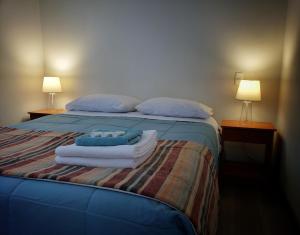 a bedroom with a bed with towels and two lamps at Cabaña Puro Ranco in Lago Ranco