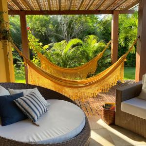 eine Hängematte auf einer abgeschirmten Veranda mit einem Sofa in der Unterkunft Costa do Sauipe Casa dentro do complexo hoteleiro in Costa do Sauipe