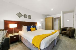a hotel room with a large bed and a chair at The Alps Apartment Three Bedroom in Queenstown