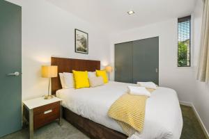 a bedroom with a large bed with yellow pillows at The Alps Apartment Three Bedroom in Queenstown