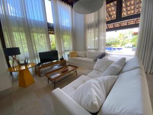 a living room with white furniture and large windows at Costa do Sauipe Casa dentro do complexo hoteleiro in Costa do Sauipe