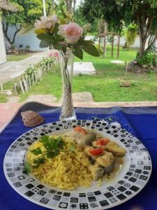 une assiette de nourriture sur une table avec un vase de roses dans l'établissement Chalé da Vovó, à Soure
