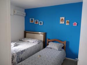 two beds in a room with a blue wall at CASA in Piranhas