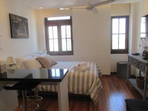 a bedroom with a bed and a table and two windows at Apartamento en el palacio salvo candombe in Montevideo
