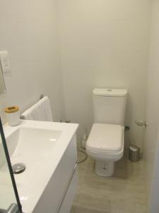 a white bathroom with a toilet and a sink at Apartamento en el palacio salvo candombe in Montevideo