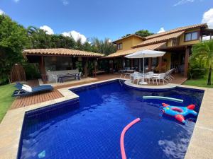 a swimming pool with a pool noodle in front of a house at Costa do Sauipe Casa dentro do complexo hoteleiro in Costa do Sauipe