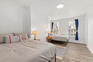 a white bedroom with two beds and a window at Orange Oasis in the Heart of East Rock with FREE parking near DT and Yale in New Haven