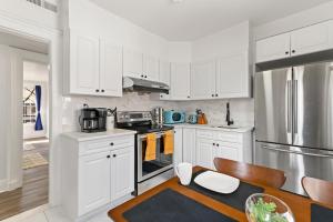 a kitchen with white cabinets and a stainless steel refrigerator at Orange Oasis in the Heart of East Rock with FREE parking near DT and Yale in New Haven