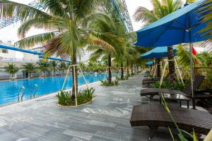 a resort with a pool and palm trees and chairs at Hoang Hung Hotel in Dĩ An