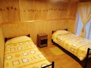 a room with two beds in a wooden room at Cabañas camelia in Puelo