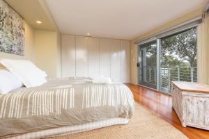 een slaapkamer met een bed en een groot raam bij Laaqua in Blueys Beach
