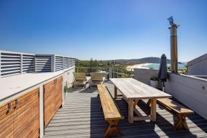 een houten terras met een picknicktafel op een balkon bij Laaqua in Blueys Beach