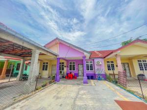 une rangée de maisons aux couleurs violette et jaune dans l'établissement Nail Homestay Kuala Besut, à Kampung Kuala Besut
