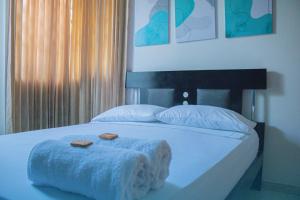 ein weißes Bett mit zwei Handtüchern und zwei Kissen in der Unterkunft Casa Hostal Rico Vacile in Valledupar