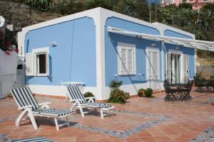 蓬扎的住宿－Maridea - Torpedine Marezzata，两把椅子坐在蓝色建筑前的庭院