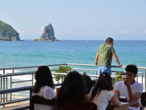 a group of people sitting at a table by the ocean at Pink Palace Beach Resort in Agios Gordios
