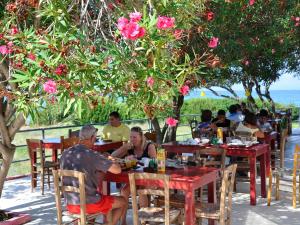 a group of people sitting at tables at a restaurant at Pink Palace Beach Resort in Agios Gordios