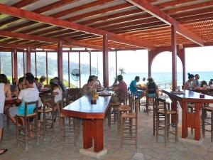 a group of people sitting at tables in a restaurant at Pink Palace Beach Resort in Agios Gordios