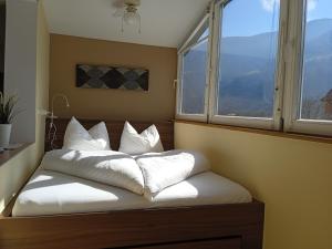 a bed with white pillows sitting in a room with windows at Apartment Himmelreich 29 in Plaus