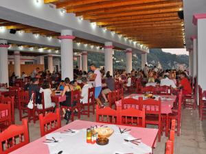 a large group of people sitting at tables in a restaurant at Pink Palace Beach Resort in Agios Gordios