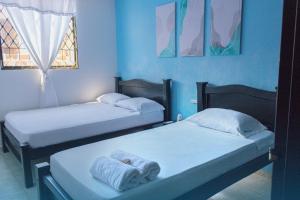 2 Betten in einem Zimmer mit blauen Wänden in der Unterkunft Casa Hostal Rico Vacile in Valledupar
