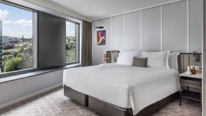um quarto com uma grande cama branca e janelas grandes em Cordis, Auckland by Langham Hospitality Group em Auckland
