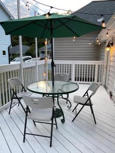 uma mesa e cadeiras num deque com um guarda-sol em Modern home with huge fenced yard and No pet fees em Durham