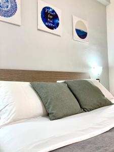 ein Schlafzimmer mit einem weißen Bett mit zwei grünen Kissen in der Unterkunft POMPEI FELIX in Pompei