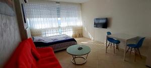 Habitación pequeña con sofá rojo y mesa. en Sweet Honeymoon Apartment Tel Aviv Bat Yam 611, en Bat Yam
