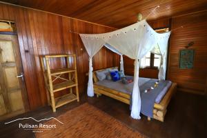a bedroom with a bed with a mosquito net at Pulisan Resort in Rinondoran