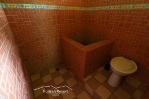 uma casa de banho com um WC numa parede de tijolos em Pulisan Resort em Rinondoran