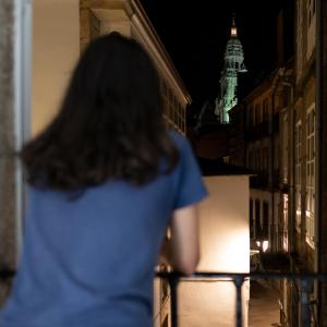 a woman walking down a city street at night at Pension Santa Cruz in Santiago de Compostela