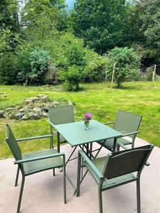 une table et des chaises avec un vase de fleurs. dans l'établissement Woodland Cottage Charleton Estate, à Colinsburgh