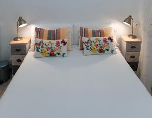 1 cama blanca con 3 almohadas y 2 lámparas en Pension Santa Cruz, en Santiago de Compostela