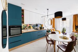 a kitchen with blue cabinets and a table with chairs at TELEKI40 Apartman Győr CENTRAL, FREE PARKING, TERRACE in Győr