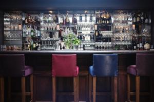 a bar with three chairs in front of a bar at Old Parsonage Hotel in Oxford