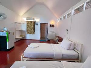 a small room with two beds and a refrigerator at Holiday Resort - SHA Plus in Ko Yao Noi