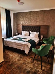 una camera con un grande letto e una sedia verde di Hotel Margaritar a Buşteni