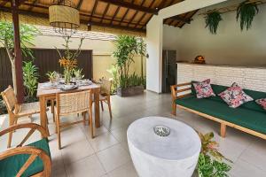 un patio con un sofá verde y una mesa en CASA BEGJA I Tranquil 2BR Villa w Private Pool in Mertanadi en Seminyak