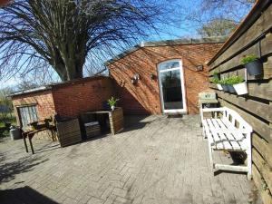 a brick building with a patio with a bench at Ferienhäuschen Alte Schmiede, 35647 in Uplengen