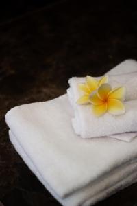 una flor amarilla encima de una toalla blanca en CASA BEGJA I Tranquil 2BR Villa w Private Pool in Mertanadi en Seminyak