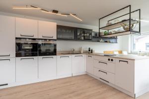 a kitchen with white cabinets and black appliances at Alpenaster 2 in Sonthofen
