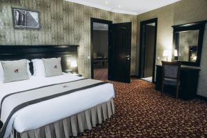 a hotel room with a large bed and a desk at Colosseum Marina Hotel in Batumi