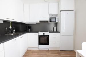 Biała kuchnia z białymi szafkami i urządzeniami w obiekcie 2ndhomes Cozy and Quiet 2BR Apartment by the Esplanade Park w Helsinkach