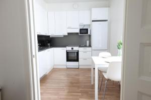 a white kitchen with white cabinets and a table at 2ndhomes Cozy and Quiet 2BR Apartment by the Esplanade Park in Helsinki